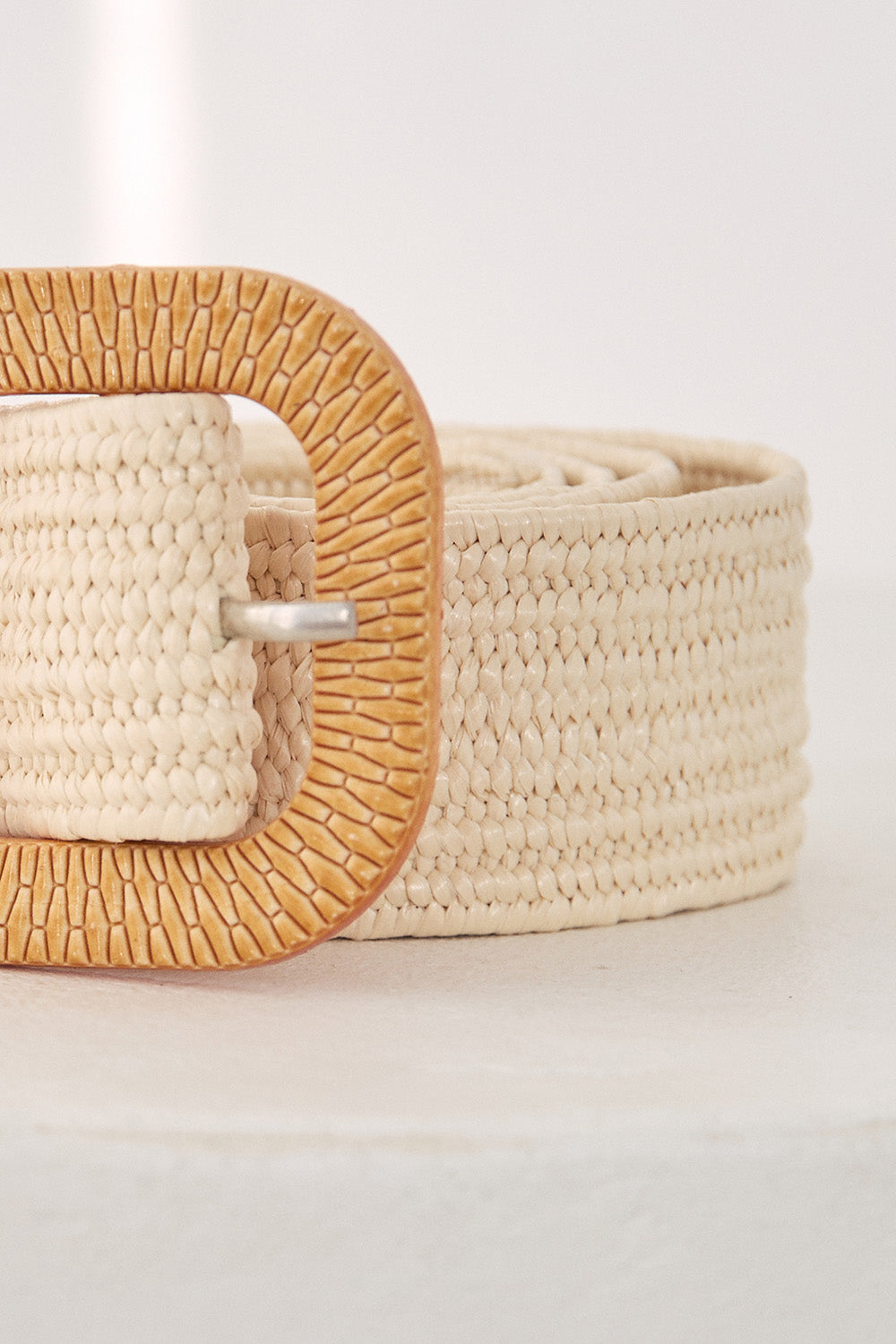 Beige woven belt with a wooden buckle on a light background