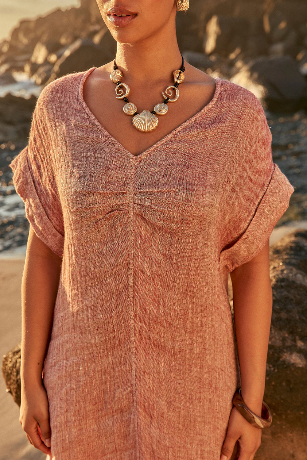 Woman wearing a pink dress with a necklace on a beach
