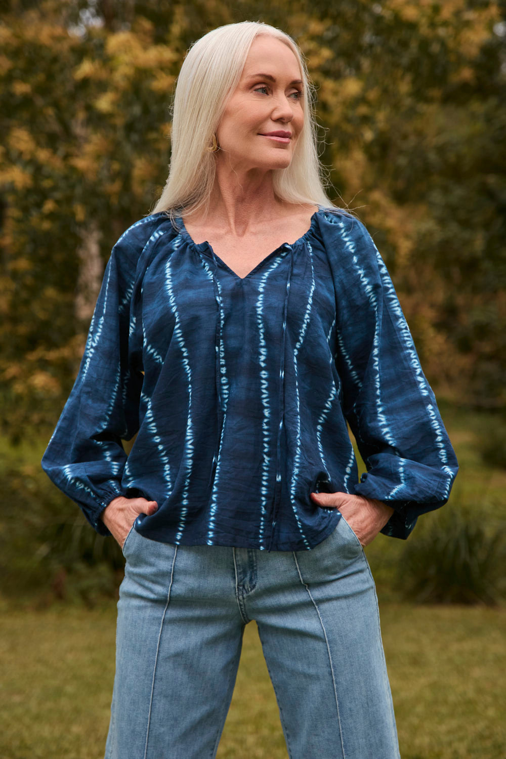 Woman wearing a blue tie-dye blouse and jeans outdoors