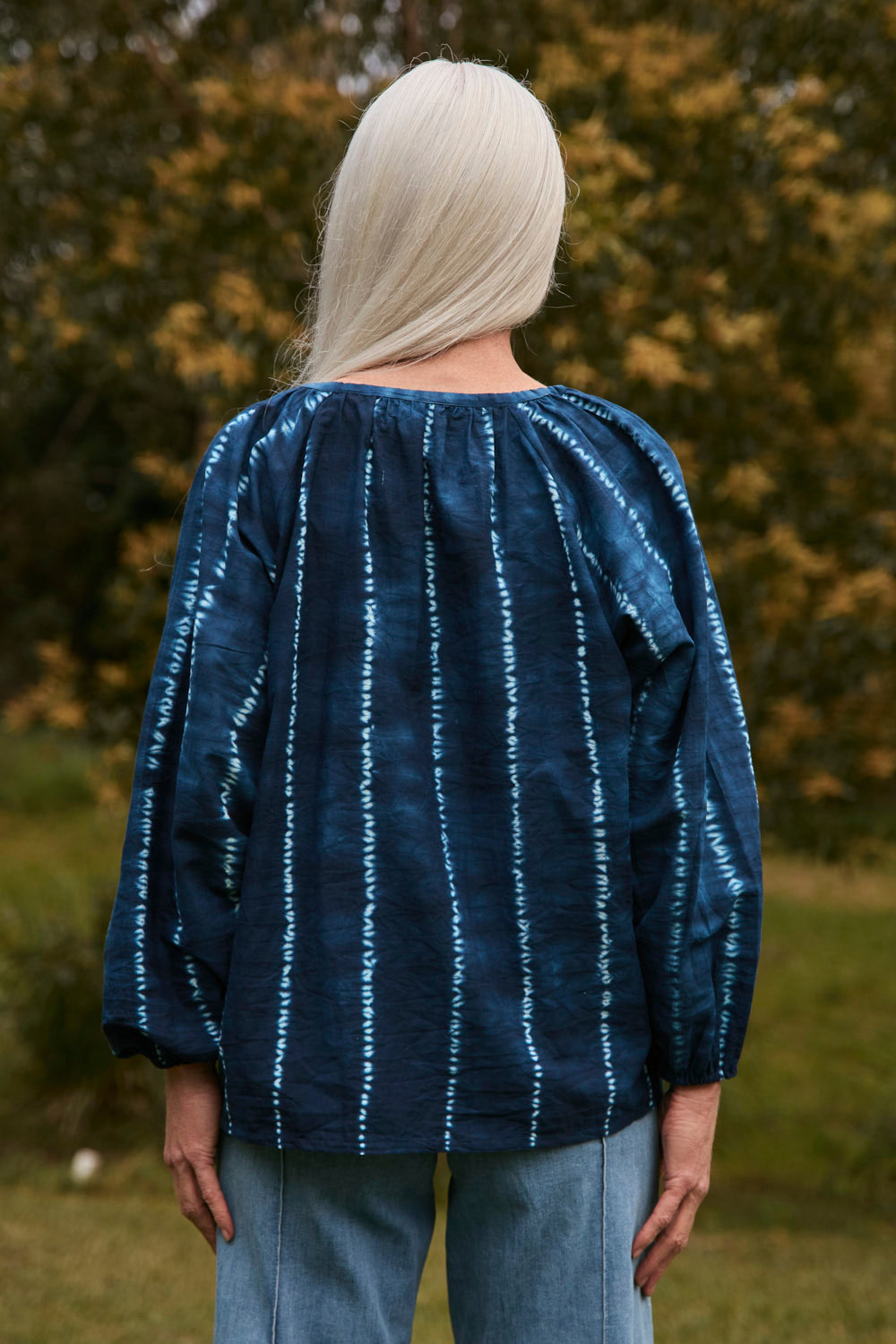 Person wearing a blue and white striped shirt with a blurred natural background