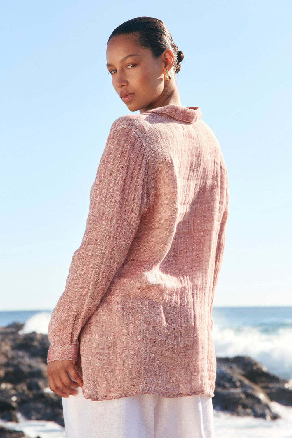 Woman wearing a pink textured sweater by the ocean